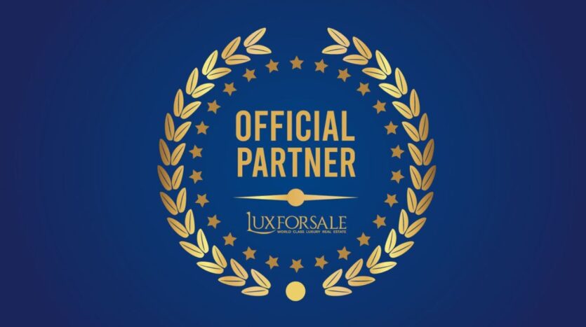 Emblema celebrativo su sfondo blu con corona d’alloro dorata e scritta centrale Official Partner Luxforsale, simbolo della partnership nel settore immobiliare di lusso.